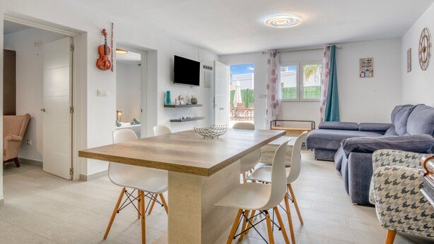 A modern living room with a sofa, a dining table with chairs, a TV, and a violin on the wall. - Villa 'Farau' with Sea View, Wi-Fi and Air Conditioning (Calpe)