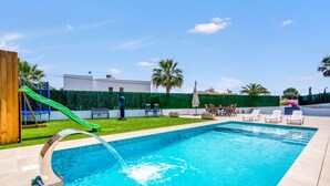 A swimming pool with a slide, lounge chairs, and a green fence. - Villa 'Farau' with Sea View, Wi-Fi and Air Conditioning (Calpe)