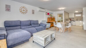 A modern living room with a grey sofa, a coffee table, and a dining area with white chairs. - Villa 'Farau' with Sea View, Wi-Fi and Air Conditioning (Calpe)