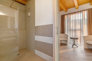 A room with a glass door, a tiled floor, a small table, and two chairs.