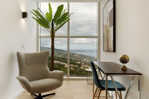 A modern room with a large window, a comfortable chair, a dining table with chairs, a potted plant, and a globe on the table. - Holiday Home 'Belavista' with Sea View, Wi-Fi and Air Conditioning (Gaula)