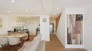Una sala de estar moderna con sofá, mesa de comedor y zona de cocina al fondo.