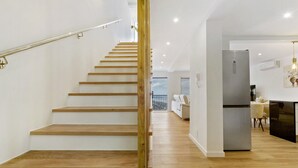 Un interior moderno con una escalera de madera, una zona de cocina y un espacio comedor.