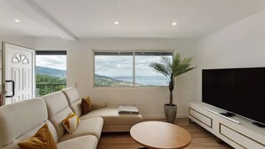 Una sala de estar moderna con un sofá, una mesa de centro, un televisor y un ventanal con vistas.