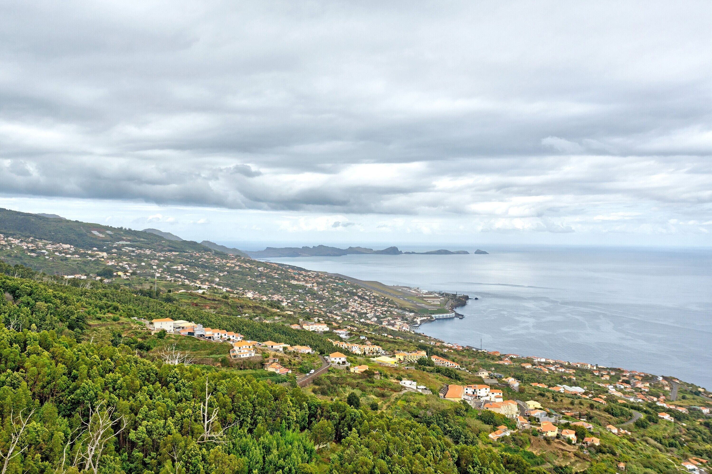Un pueblo costero con casas, vistas al mar y un paisaje montañoso.
