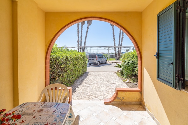 An outdoor patio with a table and chairs, a covered walkway, and a parked car.