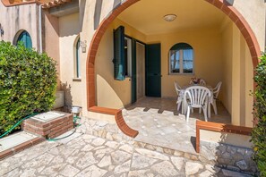 A patio with stone flooring, a brick planter, and white outdoor furniture. - Apartment 'Lorenzo' with Sea View, Wi-Fi and Air Conditioning (Marzamemi)