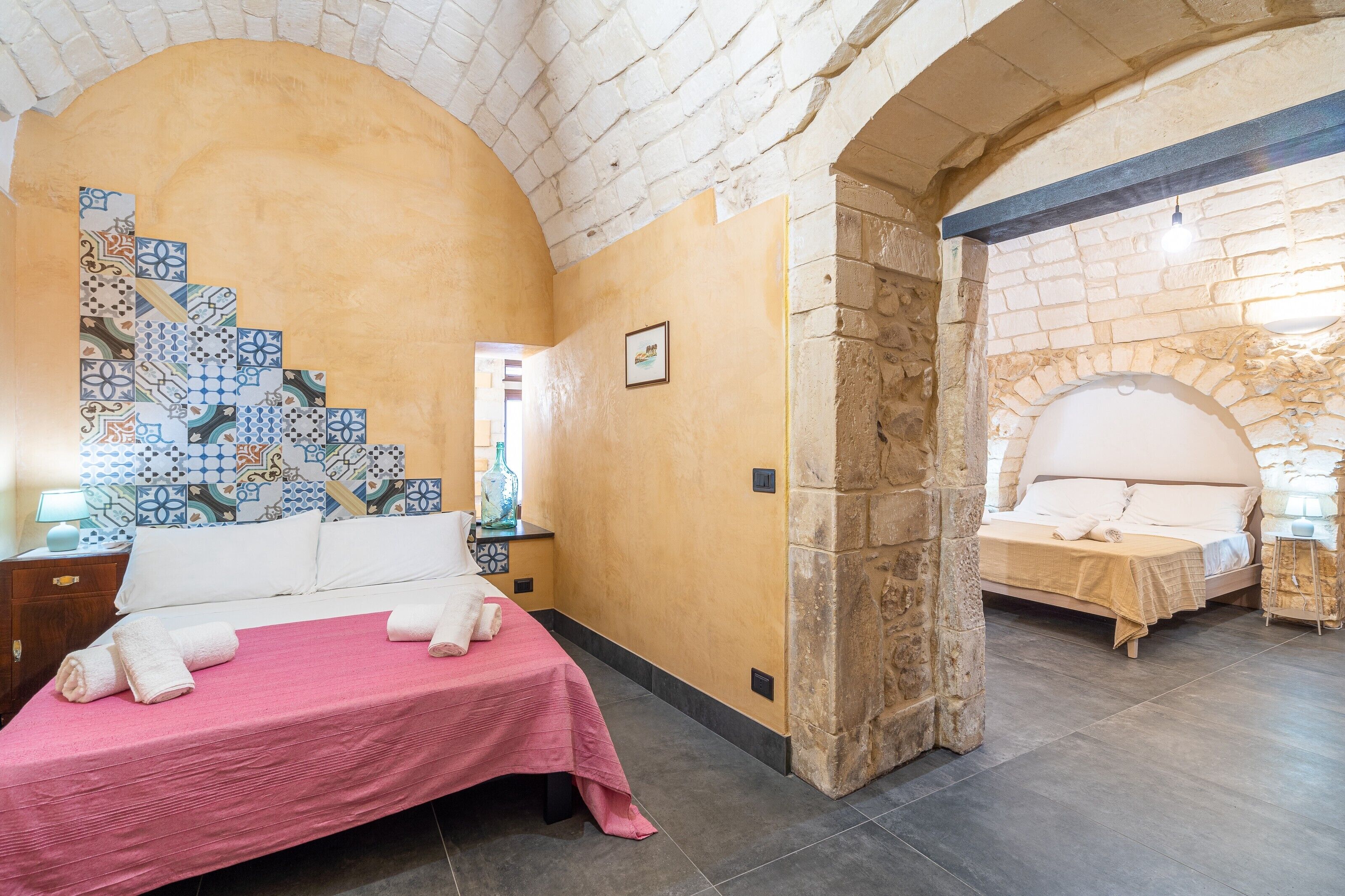 Une chambre d’hôtel avec un lit, une table de chevet, une lampe et un mur décoratif.