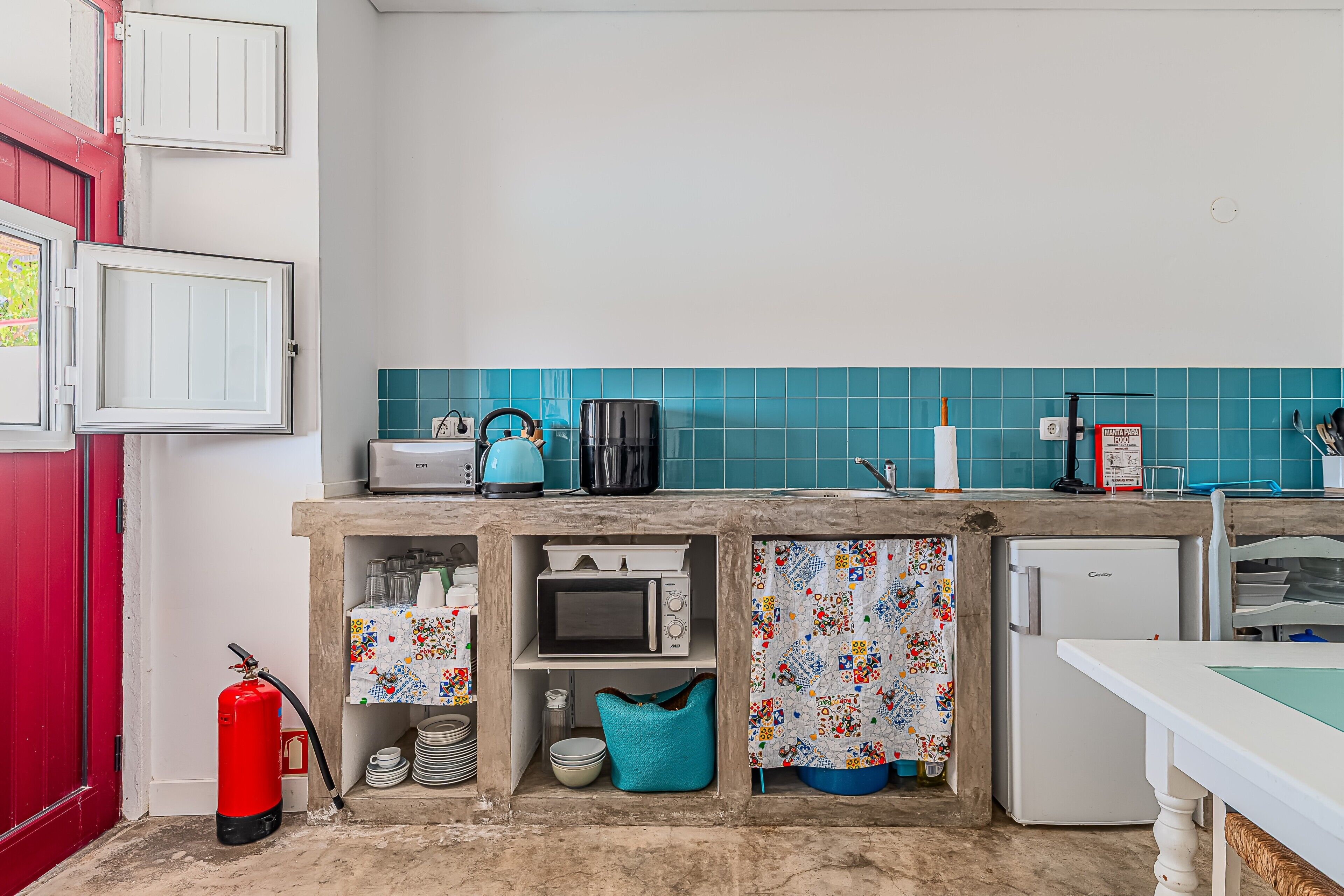 Eine Küche mit Mikrowelle, Toaster, Kaffeemaschine und einem kleinen Kühlschrank.