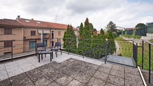 A rooftop terrace with outdoor seating, a view of surrounding buildings, and a metal railing. - Apartment 'Blu' with Shared Terrace and Wi-Fi (Fabbrica Durini)