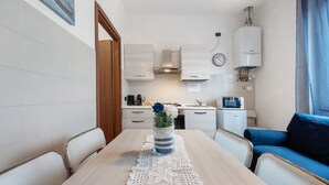 A compact kitchen with white cabinets, a clock, and a microwave. - Apartment 'Blu' with Shared Terrace and Wi-Fi (Fabbrica Durini)