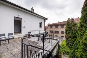 A rooftop terrace with outdoor seating and a staircase leading to a second floor.
