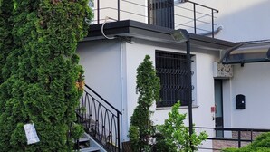 A building with a white exterior, a black metal staircase, and a small garden area with a statue. - Apartment 'Blu' with Shared Terrace and Wi-Fi (Fabbrica Durini)