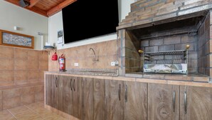 Una cocina con horno de ladrillo, armarios de madera y salpicadero de azulejos.