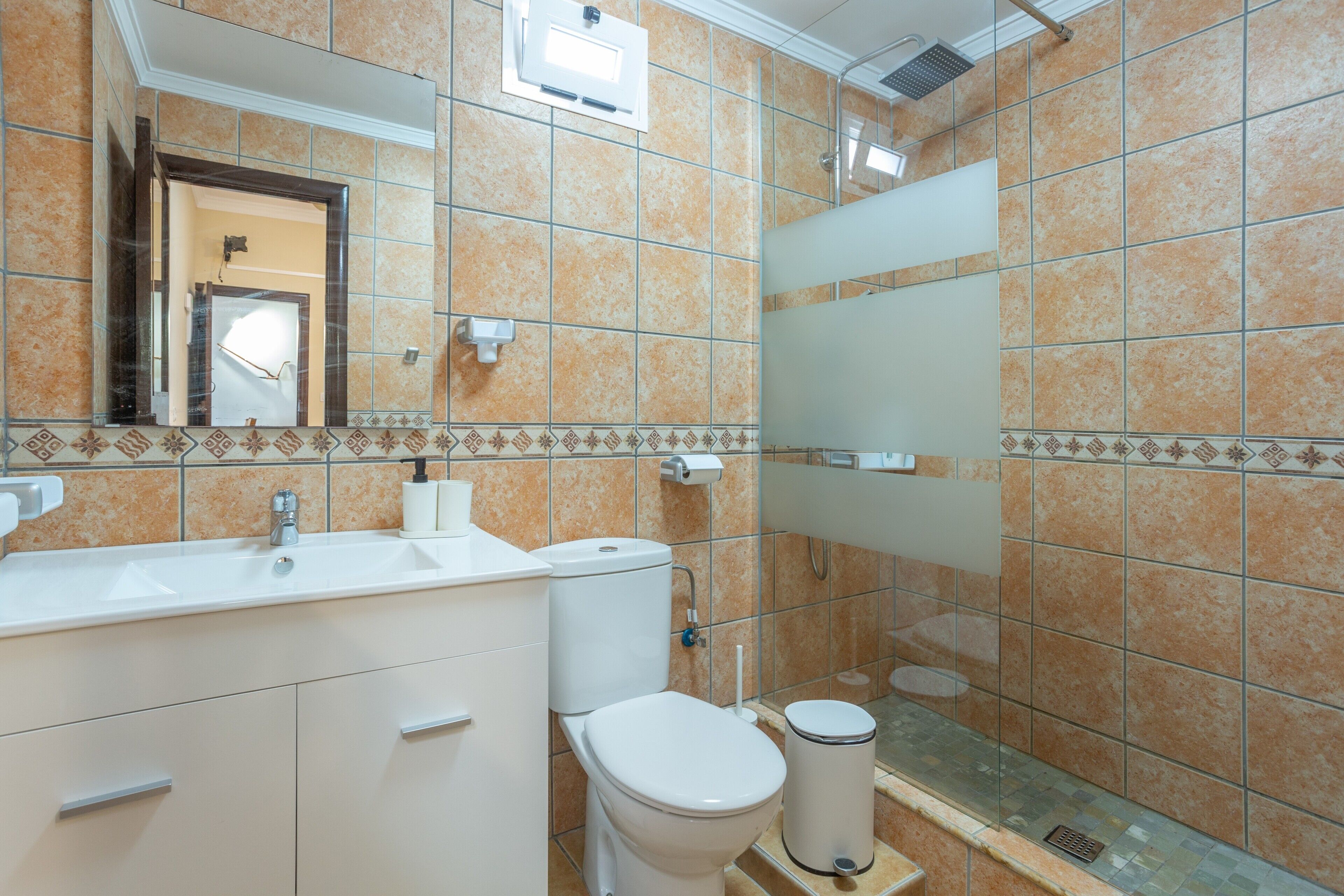 A bathroom with a sink, toilet, and mirror.