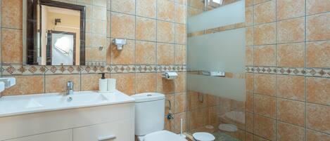 A bathroom with a sink, toilet, and mirror.