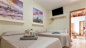 Un dormitorio con dos camas, un televisor y obras de arte en las paredes.