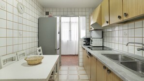A kitchen with a refrigerator, microwave, sink, and a dining table with chairs.
