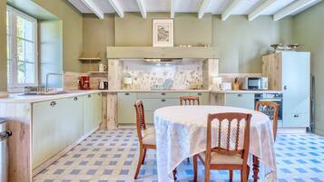 Una cocina con una mesa de comedor, sillas, microondas y estufa.