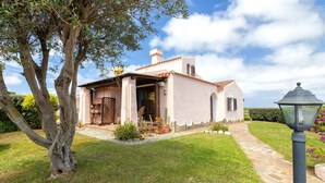 A house with a stone pathway leading to the entrance, a tree in the foreground, and a lamp post on the right. - Villa 'Sofia' with Mountain View, Wi-Fi and Air Conditioning (Punta de Su Turrione)