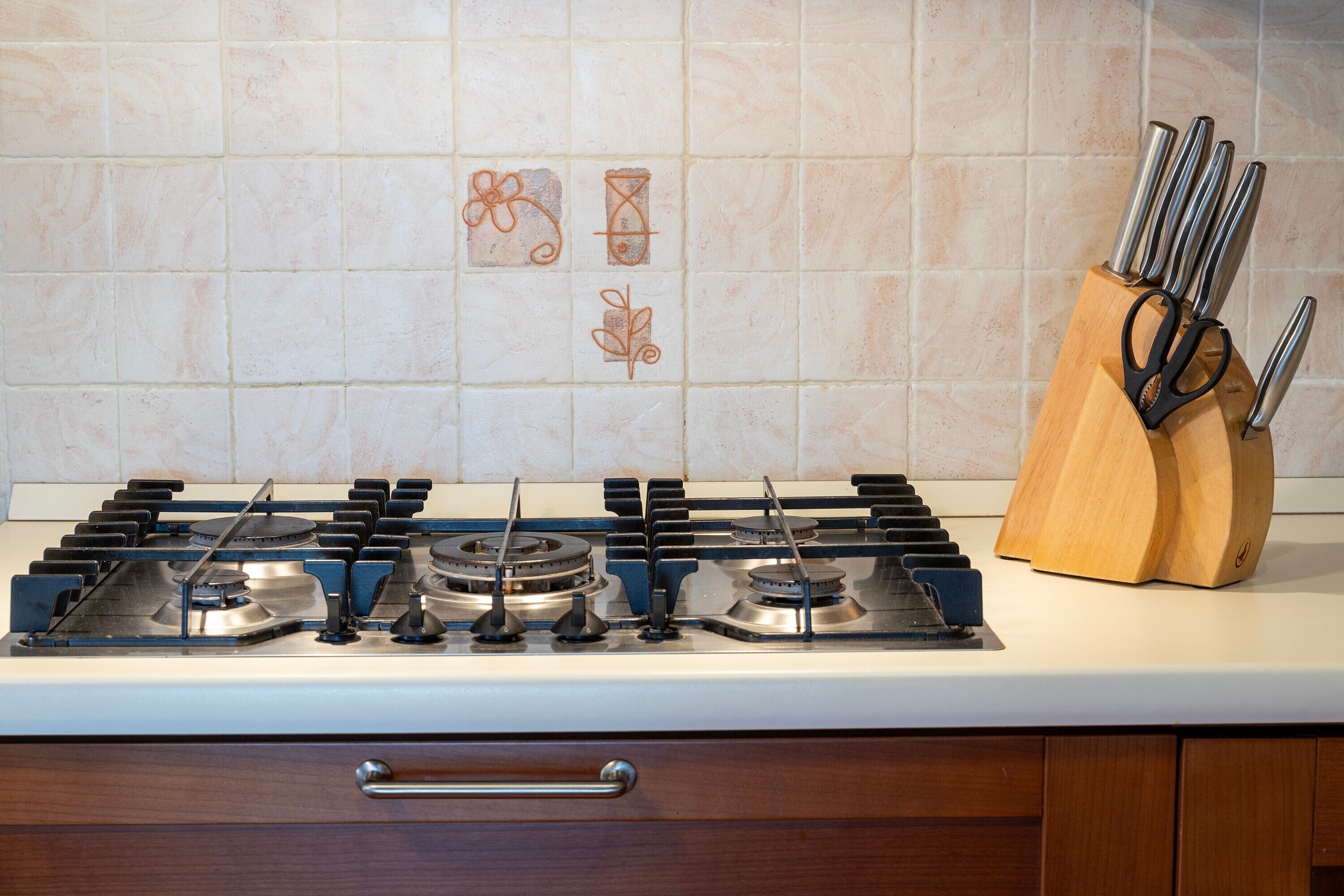 A kitchen with a gas stove, a wooden utensil holder, and a tiled backsplash.