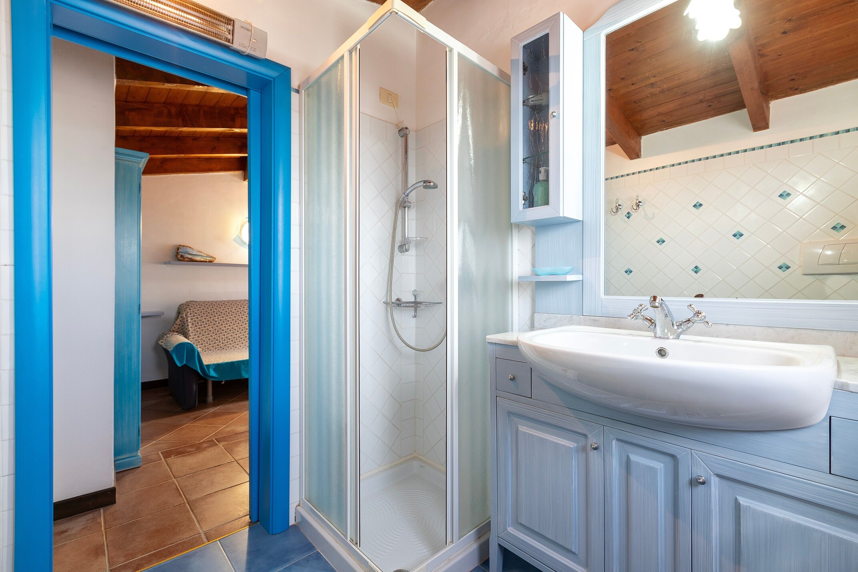 A bathroom with a glass-enclosed shower, a white sink, and a tiled backsplash.