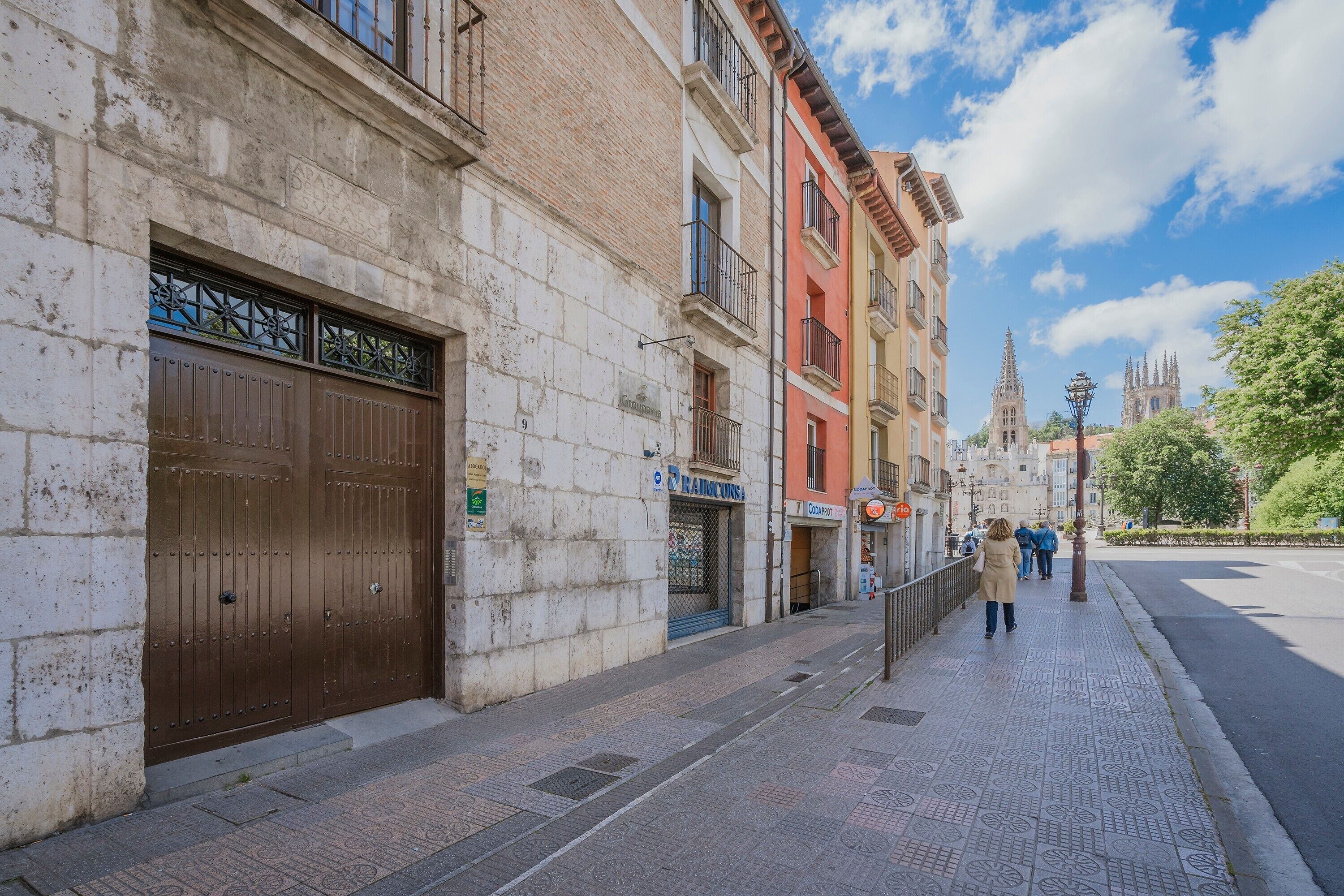 A street with buildings, a large brown gate, and a clear sky.