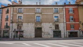 Un edificio de varios pisos con entrada central, balcones y locales comerciales.