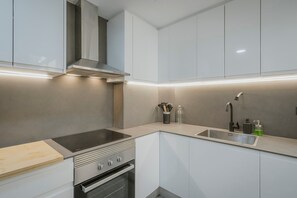 Une cuisine moderne dotée d’une cuisinière, d’un four et d’un évier intégrés, ainsi que de meubles de rangement et d’un éclairage sous les meubles.