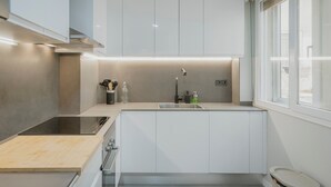 A modern kitchen with white cabinets, a stainless steel sink, and a window providing natural light.