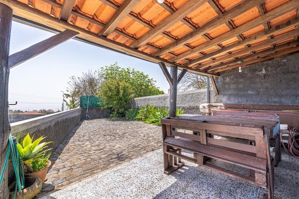Une terrasse sur le toit, avec un banc en bois, des plantes en pot et un sol recouvert de carreaux de pierre.
