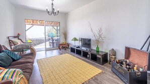 A modern living room with a sofa, TV, and decorative items. - Country House 'Serrão' with Private Terrace, Private Garden and Wi-Fi (Calheta)