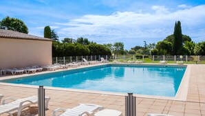 En swimmingpool med liggestole og fliseterrasse.