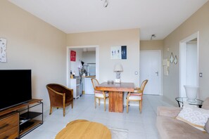 Een moderne woonkamer met een flatscreen televisie, een houten eettafel en comfortabele zithoek.