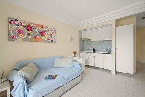 A room with a sofa, a kitchen area, and a decorative painting. - Vacation Apartment 'Complejo 206' with Sea View, Shared Pool and Wi-Fi (Costa Adeje)