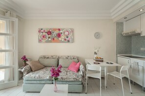 Quarto moderno com uma cama, uma mesinha, uma cadeira e uma cozinha compacta.