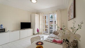 A modern living room with a flat-screen TV, dining table with fruit, a sofa, and a balcony with a view. - Vacation Apartment 'Complejo 206' with Sea View, Shared Pool and Wi-Fi (Costa Adeje)
