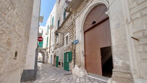 Une ruelle pavée étroite, bordée de bâtiments historiques, un panneau d’interdiction de circulation et un panneau de signalisation bleu.