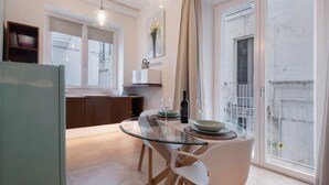 A modern kitchen with a glass dining table, white chairs, and a view of the outside. - Apartment 'Ulivo' with Wi-Fi and Air Conditioning (Monopoli)