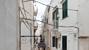 A narrow street with white buildings, balconies, and a hanging lamp. - Apartment 'Ulivo' with Wi-Fi and Air Conditioning (Monopoli)
