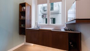 A kitchen with wooden cabinets, a window with a view of a balcony, and a built-in microwave. - Apartment 'Ulivo' with Wi-Fi and Air Conditioning (Monopoli)