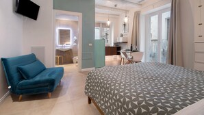 A bedroom with a bed, a sofa, a desk, and a bathroom visible through an open door. - Apartment 'Ulivo' with Wi-Fi and Air Conditioning (Monopoli)