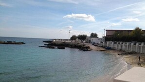 A coastal beach with clear water, a rocky outcrop, and a small pier. - Apartment 'Pescatore' with Wi-Fi and Air Conditioning (Monopoli)