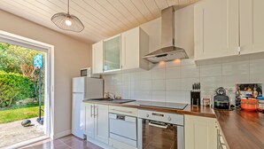 A modern kitchen with white cabinets, a wooden countertop, a built-in oven, and a stainless steel range hood.