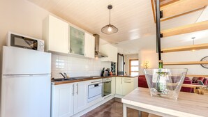 A modern kitchen with white cabinets, a built-in oven, a microwave, and a dining area with a table and chairs.
