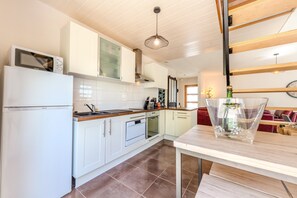 A modern kitchen with white cabinets, a built-in oven, a microwave, and a dining area with a table and chairs.