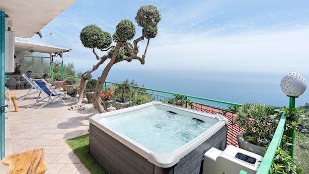 Un jacuzzi con vista al mar, un árbol y mobiliario de exterior.