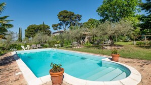 A rectangular swimming pool with a curved edge, surrounded by a brick patio. - Apartment 'Merlot, 4' with Private Garden and Wi-Fi (Montefalco)