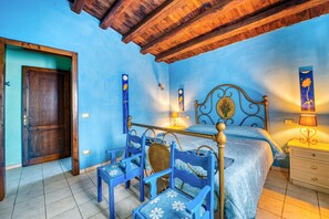 Una habitación con techo de madera, una cama con cabecera, dos mesitas de noche y una puerta.
