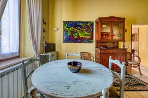 A dining area with a round table, chairs, a cabinet, and a painting on the wall.